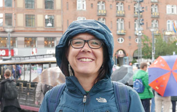 Birgit standing in a rainy city with buildings behind her